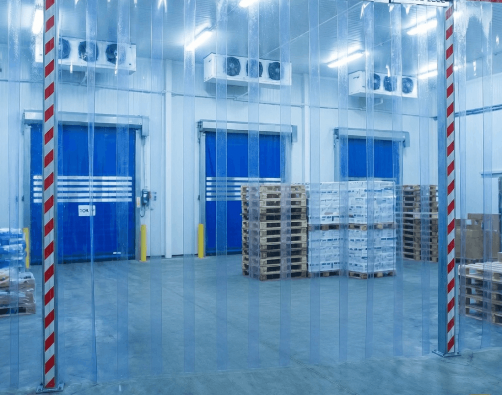 Blick durch einen PVC-Streifenvorhang auf Verladetore in einem industriellen Kühllager zur Thermoisolierung.