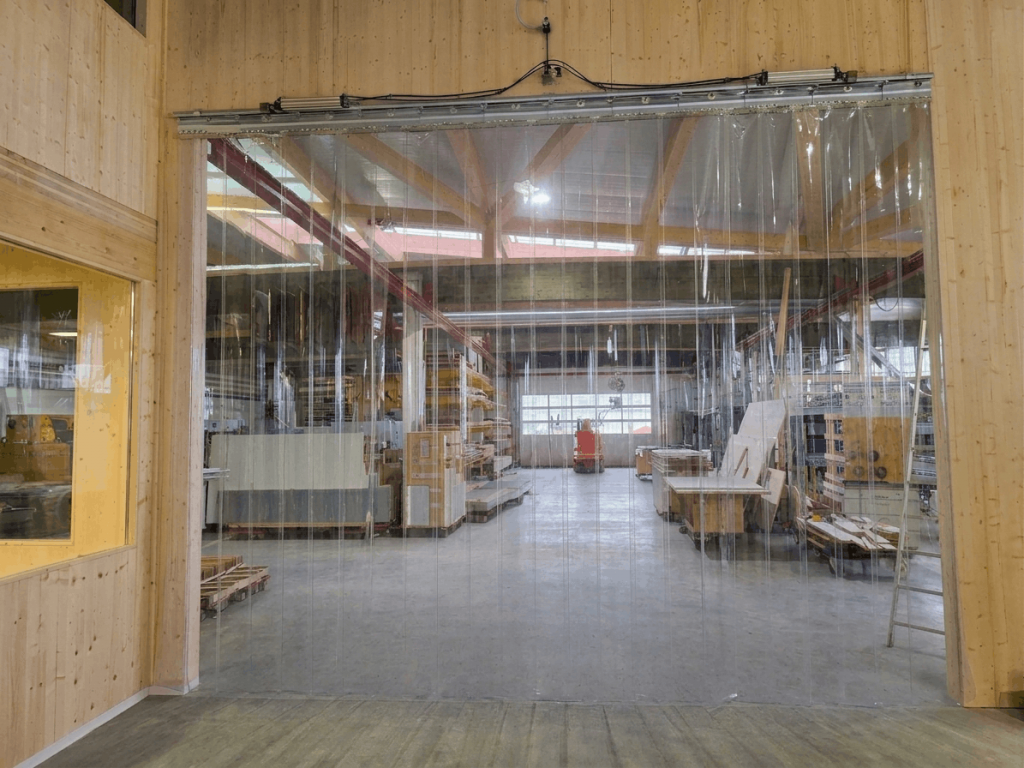 Transparenter PVC-Streifenvorhang in Lagerhalle zur flexiblen Raumtrennung und sicheren Staplerdurchfahrt