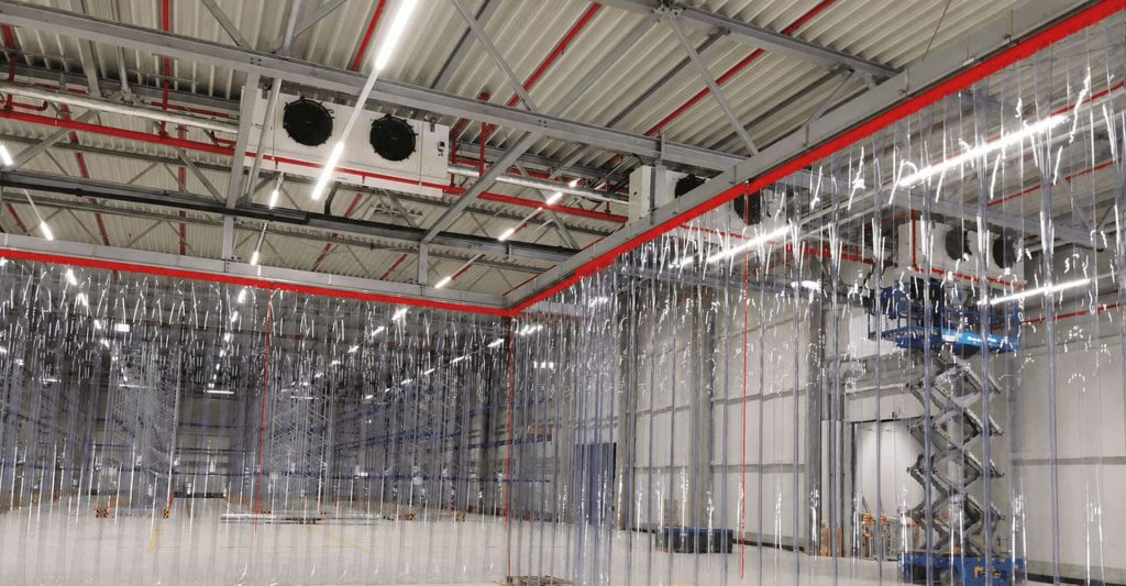 Raumhohe Hallenabtrennung aus transparenten PVC-Streifen zum Staubschutz in einer Industriehalle – EASY HANG