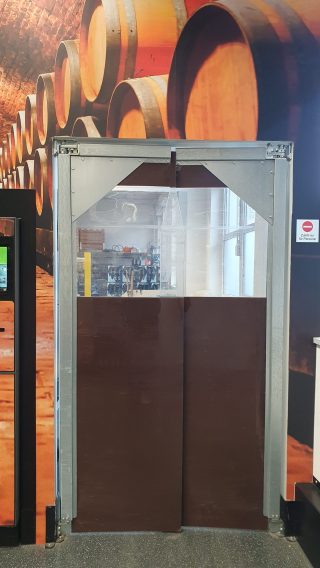 Blick durch einen PVC-Streifenvorhang in einen Weinkeller zur optimalen Temperatur- und Luftfeuchtigkeitskontrolle.