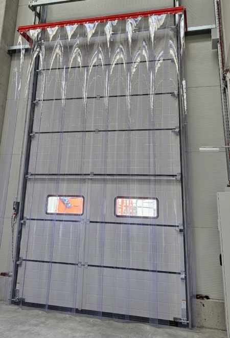 Innenansicht eines Sektionaltors mit montiertem PVC-Streifenvorhang zur Kälteisolierung in einer Lagerhalle.
